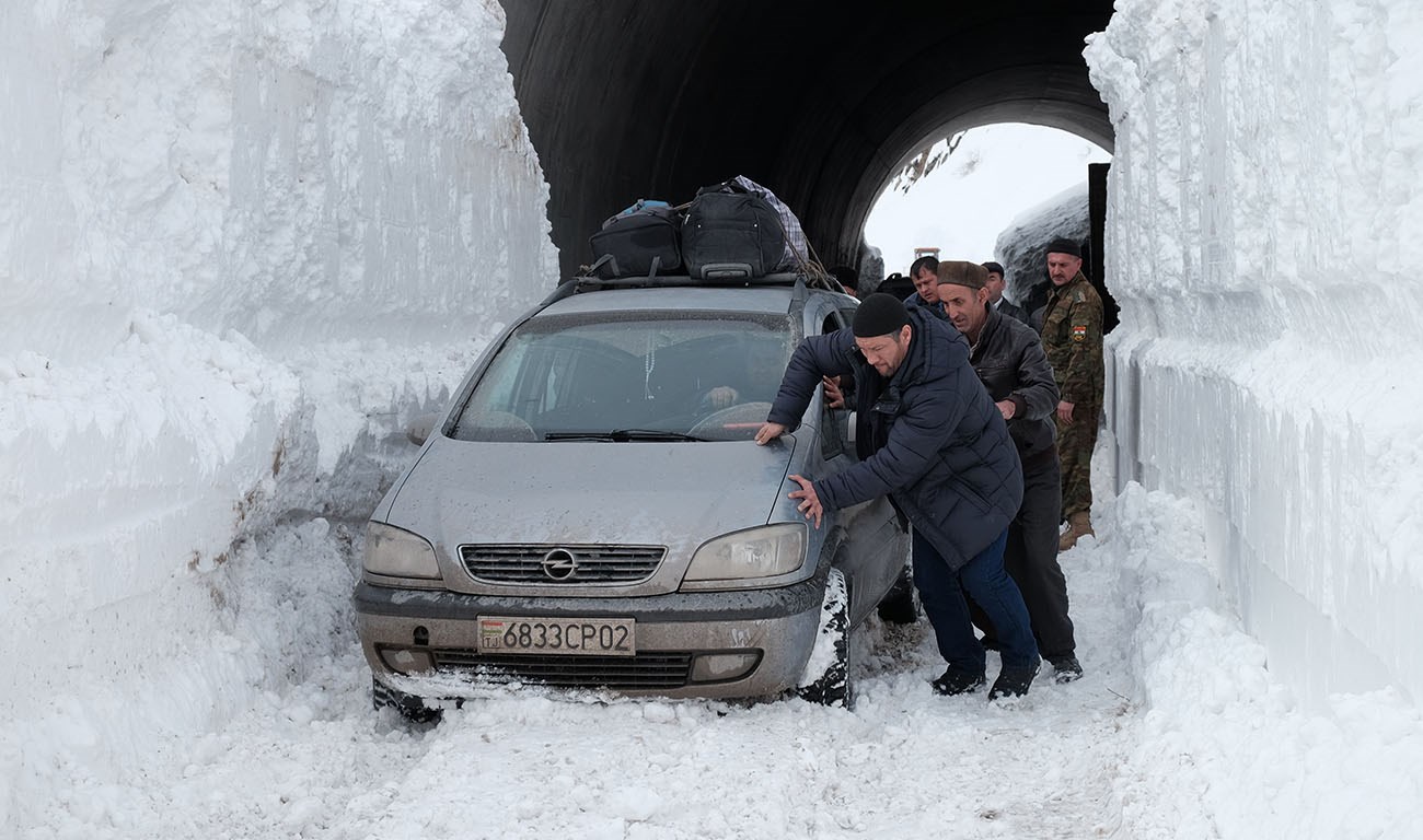 Спасатели вместе с водителями вытаскивают машину, застрявшую из-за лавин на трассе Душанбе-Худжанд